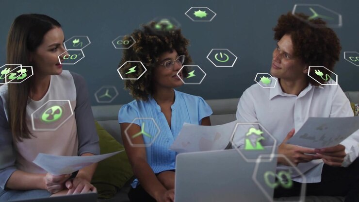 Relatore centrale che presenta un'attività toccando il laptop, con un team che legge documenti e sovrapposizione di icone verdi.