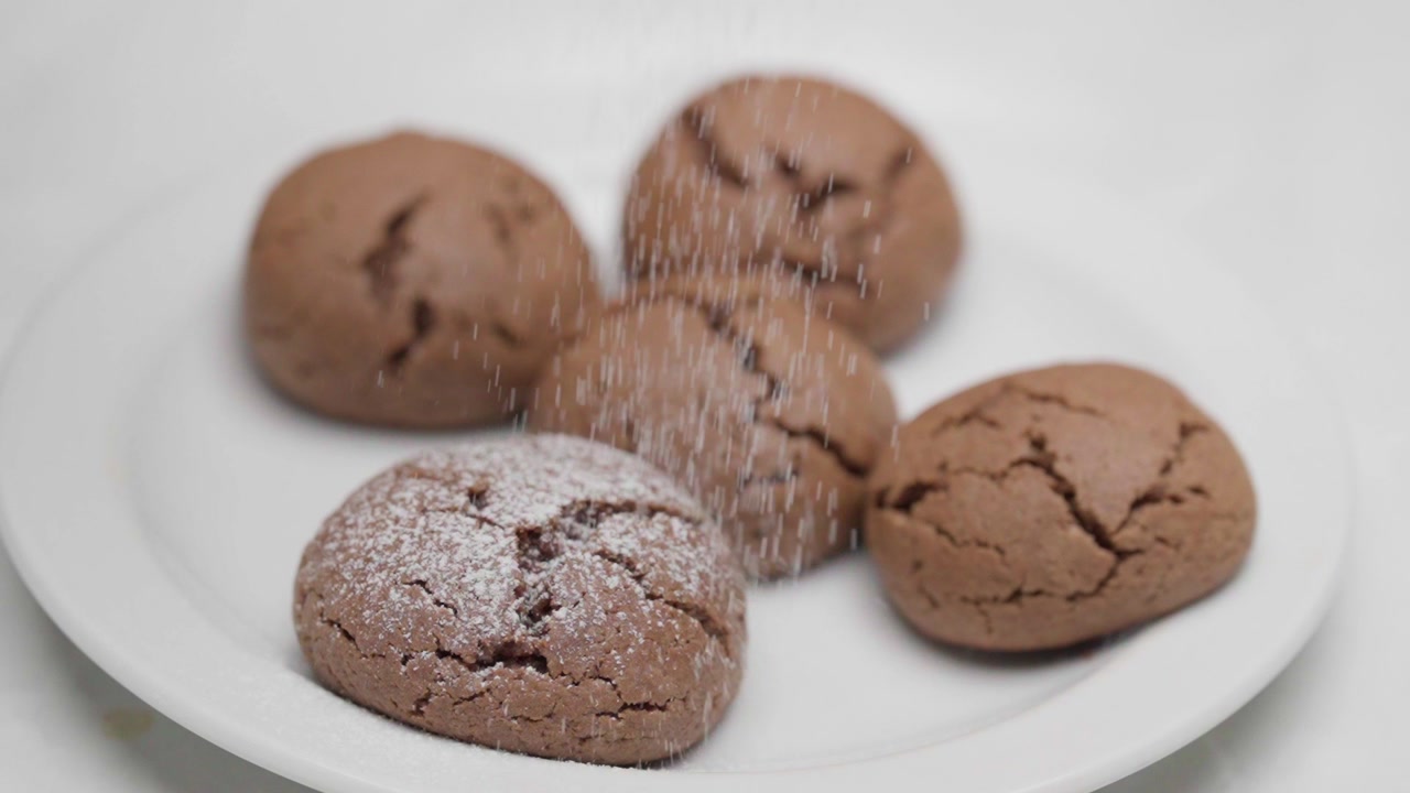 Slow motion powdered sugar falling over freshly baked chocolate cookies