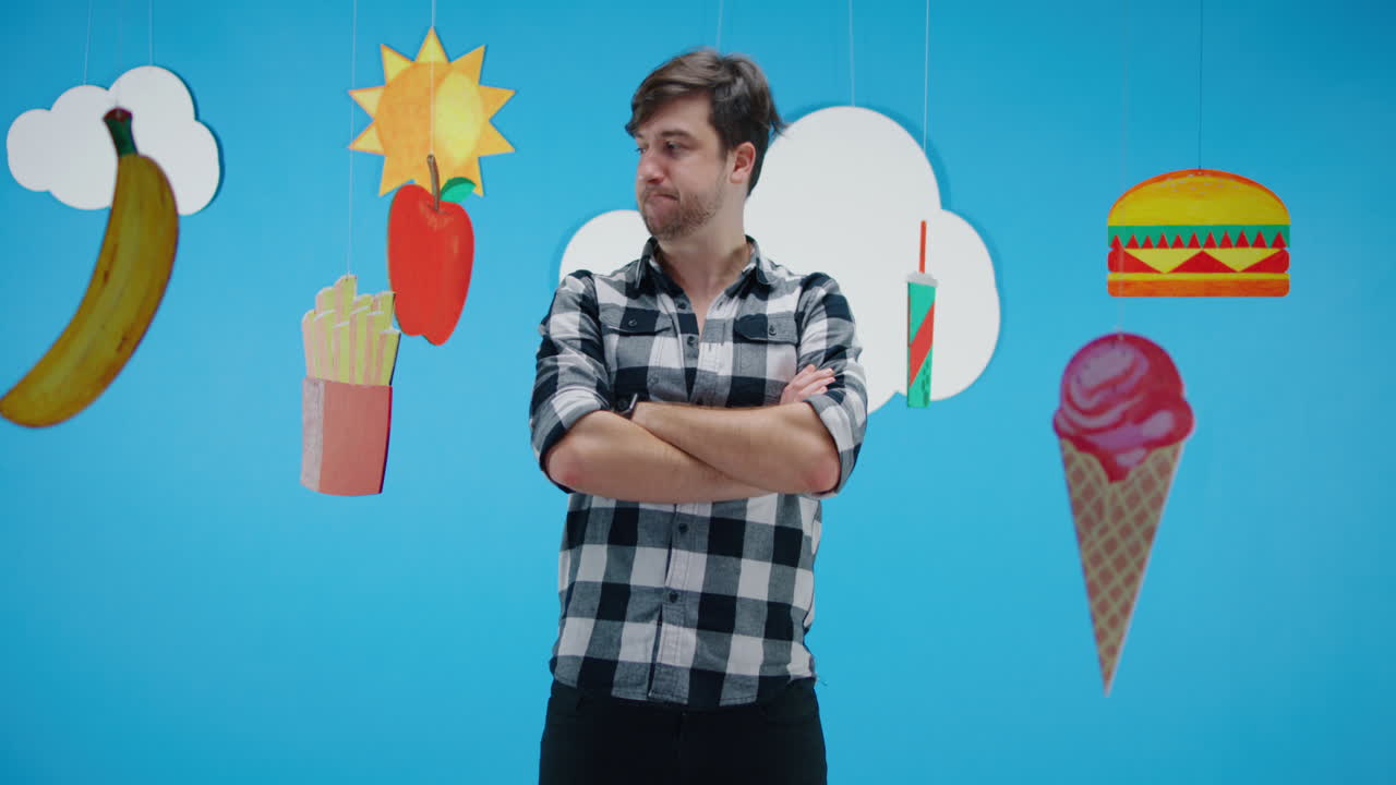 Man with arms crossed in front of food decorations