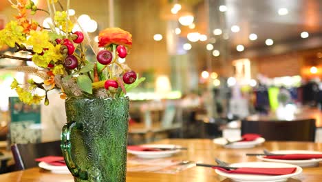 a colorful flower vase adorns a restaurant table in bangkok, with warm lighting and a bustling background atmosphere