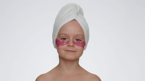 smiling child girl applying pink patches under eyes, teenager natural skin care, perfect fresh clean