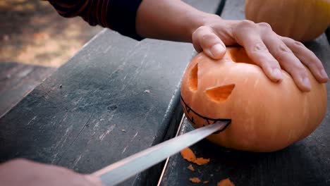 slicing a smile on a scary halloween pumpkin