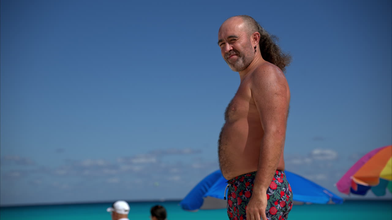 cámara lenta de un hipster alternativo mexicano latino con algo de sobrepeso y un corte de pelo loco bronceándose y disfrutando de la playa en cancún