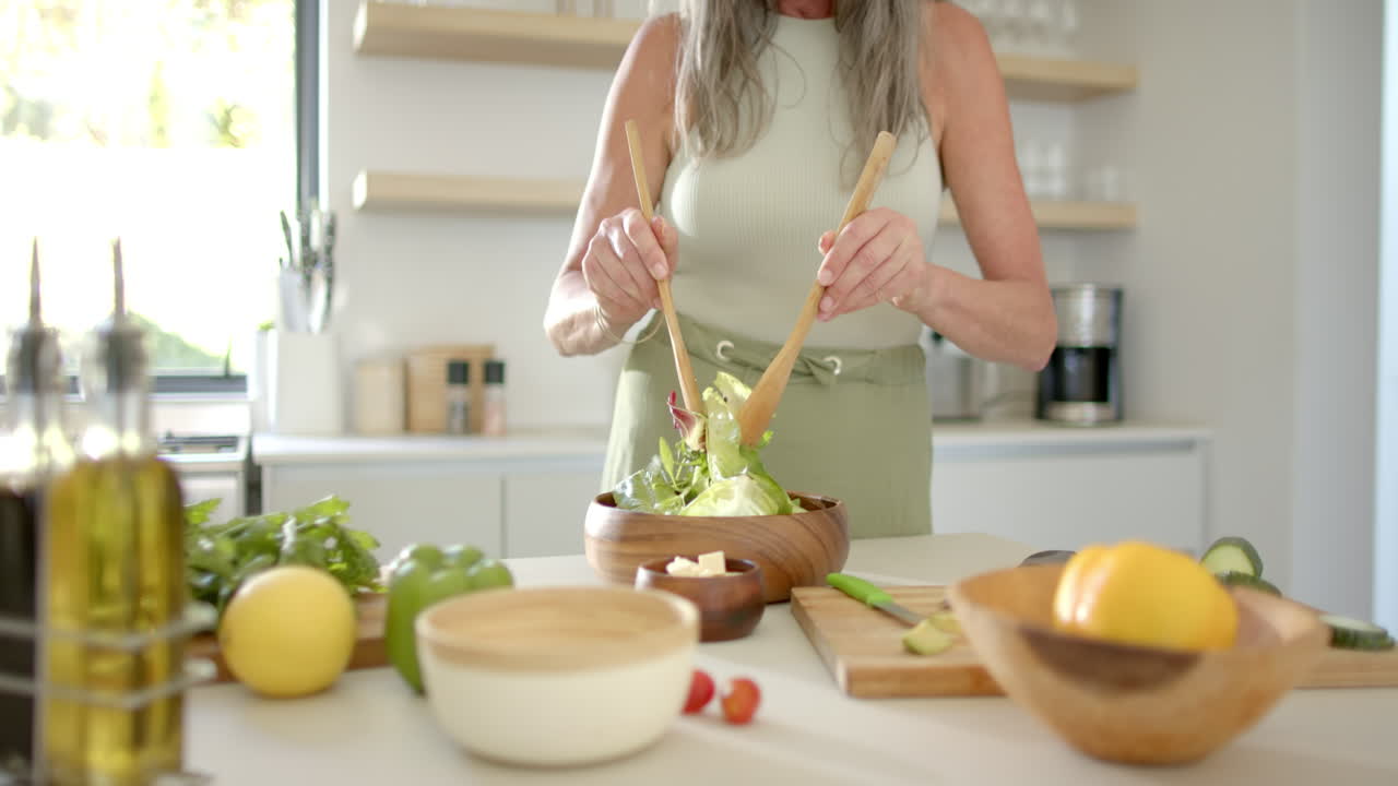 Mature Caucasian woman preparing salad in kitchen
