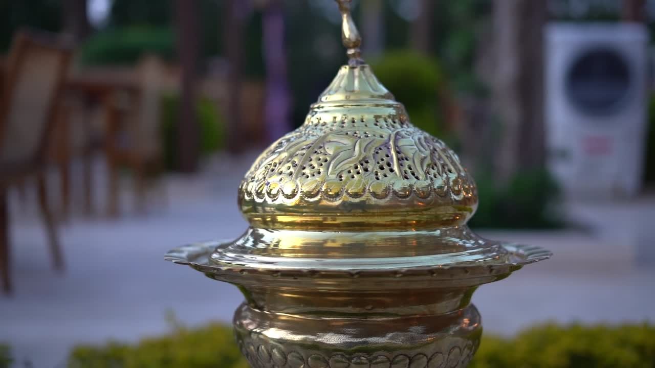 A traditional decorative lantern with Islamic motifs and a crescent moon on top, close up shot