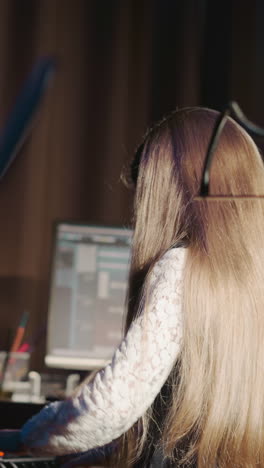 niño toca sintetizador con mentor en el estudio. niña de pelo largo aprende instrumento digital con el apoyo de un instructor en el centro de grabación de música