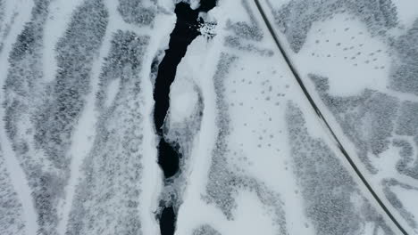 Aerial-view-looking-down-moving-across-cold-winter-woodland-lake-in-Norbotten-Swedish-landscape