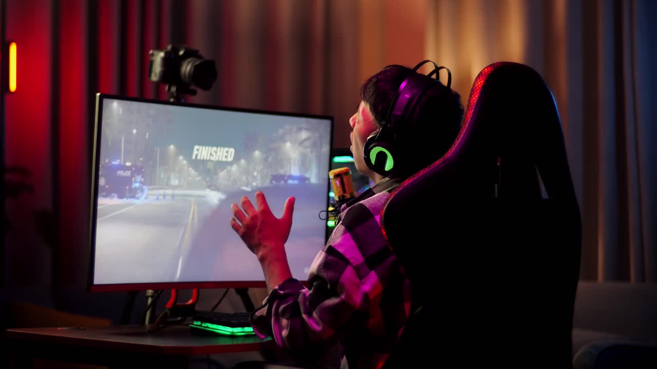 vista trasera del chico asiático streamer sintiéndose decepcionado falla en el juego de carreras de coches en la computadora personal. videojuego de transmisión en vivo, escritorio iluminado por luz de tira de led rgb