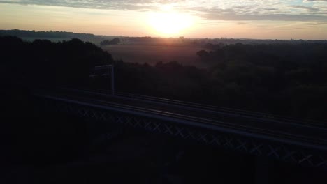 rising aerial drone footage above train bridge horizon at sunset