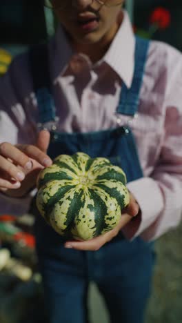 una niña con una calabaza decorativa