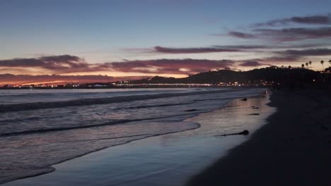 gimbal static shot of gentle ocean waves reflecting light on the beach at twilight in santa barbara, california. 4k at 48 fps slow motion