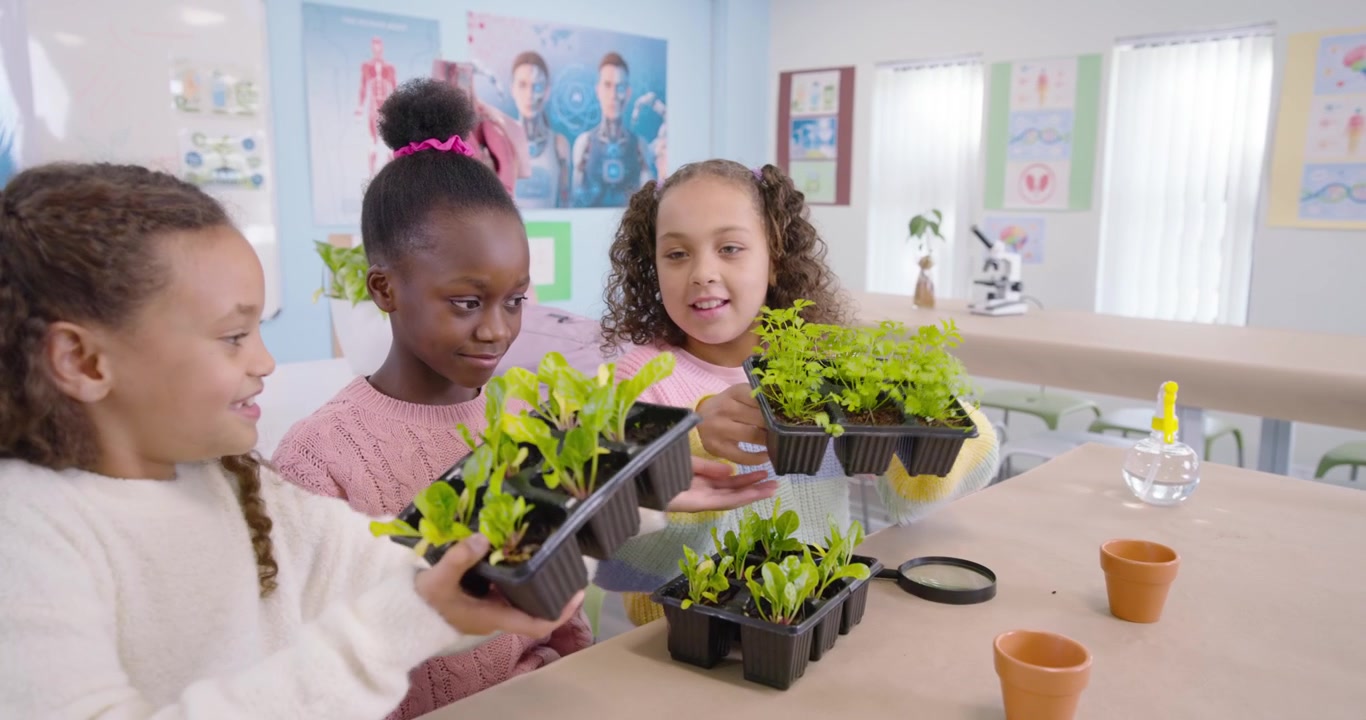 Three girls spotting leaves, inspecting seedlings in science lab using magnifier to compare growth