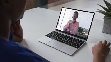 african american woman talking on video call on laptop with male office colleague at home