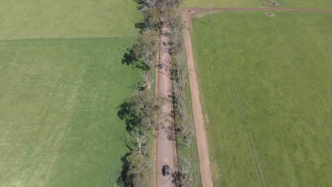 Aerial-panning-shot-top-down-to-horizon-looking-down-on-vehicle-travelling-on-a-road