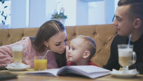 niño pequeño susurra en el oído del padre cerca de la madre sonriente