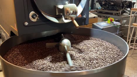 producción de café, primer plano de granos tostados girando y girando en bandeja de refrigeración, fábrica de almacén