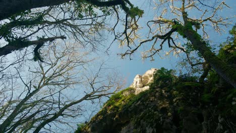 low angle view of rocky hill peak with trees and bright blue sky in dordogne region france