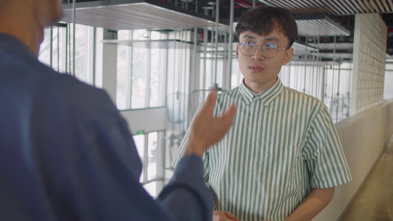 Gen Z Asian Man Talking with Coworker in Office Center
