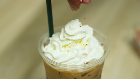 adding sprinkles to whipped cream-topped drink