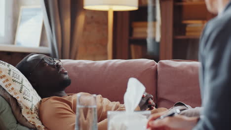 african american man lying on couch and speaking with psychologist