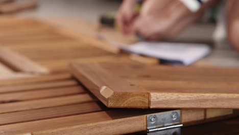 hands assembling wooden furniture, focusing on detail and craftsmanship, with a blurred background for depth