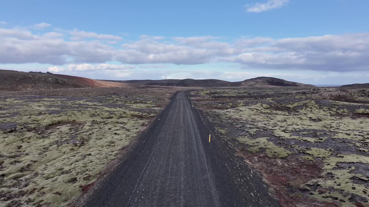 un dron captura una carretera del desierto en islandia bajo un cielo azul claro con nubes esponjosas