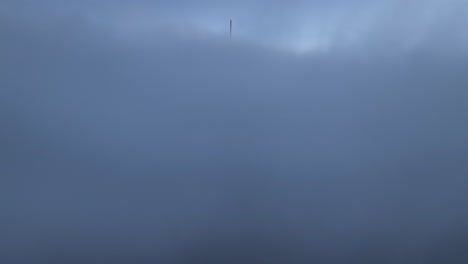 aerial shot above a cloudy foggy brisbane city, with only the tops of sky scrapers being visible