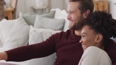 Video-of-happy-diverse-couple-watching-tv-on-sofa