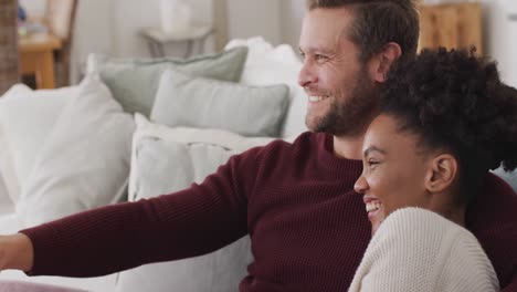 video of happy diverse couple watching tv on sofa