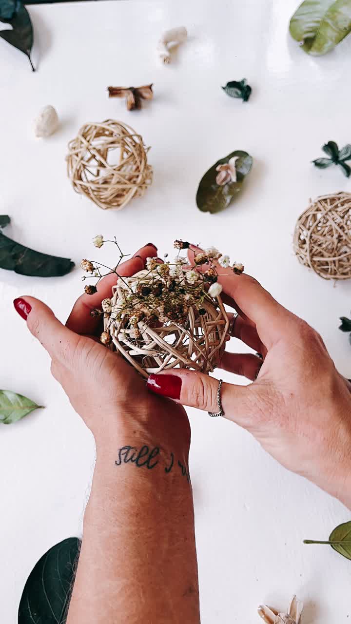 arreglo de flores secas con bolas de mimbre en la mano