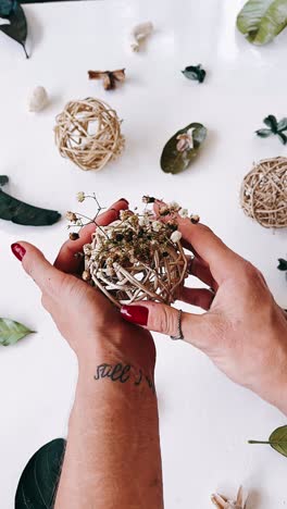 hand holding dried flower arrangement with wicker balls