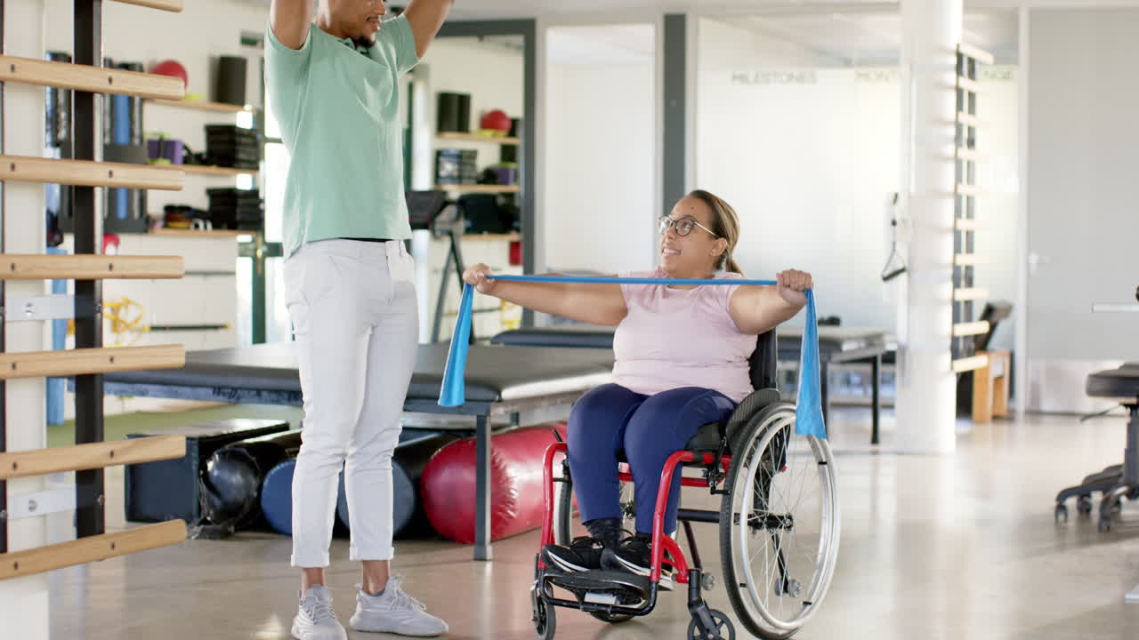 Exercise with resistance band, woman with paraplegia in wheelchair with therapist in rehabilitation