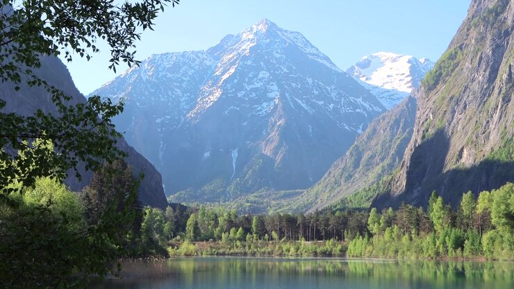 Lago turchese cristallino nelle Alpi francesi che riflette maestose montagne innevate durante una mattinata tranquilla