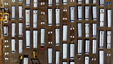 straight down aerial view of huge wind turbine tower bodies and other parts ready for construction of a wind park or wind farm