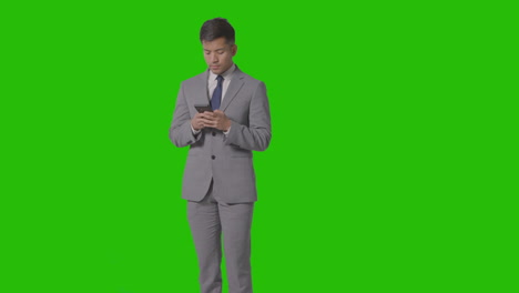 三四分之一長度的工作室拍攝, 穿著西裝的商人看著綠色屏幕上的手機 3