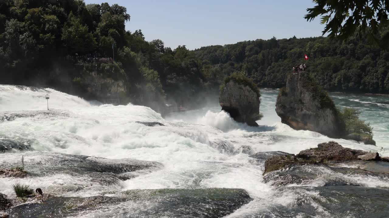 Tourists on top of the rock in the middle of Rhine falls waterfall in Switzerland