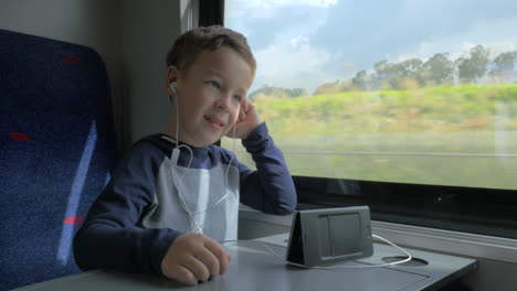 boy video chatting in train using cell and hands free set