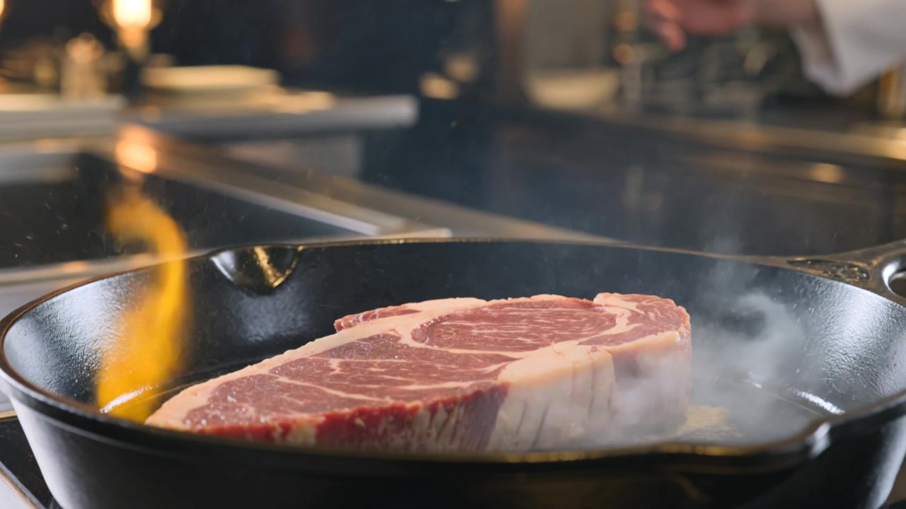 Ribeye Steak Hitting Hot Cast Iron Pan with Sizzling Butter