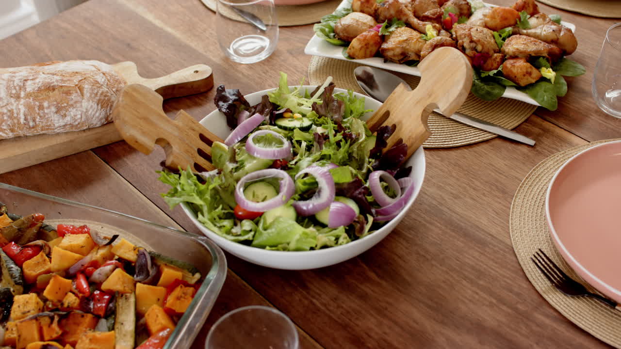 Fresh salad with red onions and roasted vegetables on wooden dining table