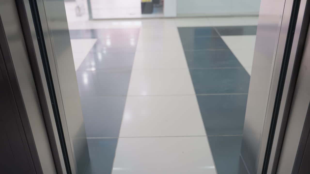 perspectiva en primera persona capturando el momento en que se abren las puertas del ascensor, revelando un elegante y moderno interior del edificio