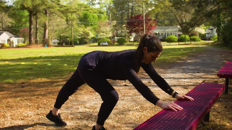 Una giovane donna vestita completamente di nero si prende del tempo per fare stretching prima di un allenamento all'aperto in un parco locale.