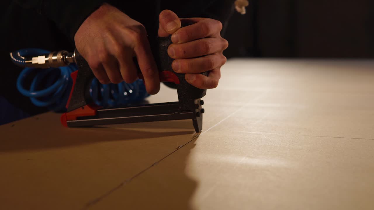 usando una pistola de clavos de aire para montar el panel de madera