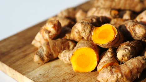 pile of turmeric roots on wooden cutting board