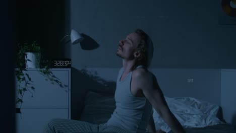 hombre sentado en la cama por la noche