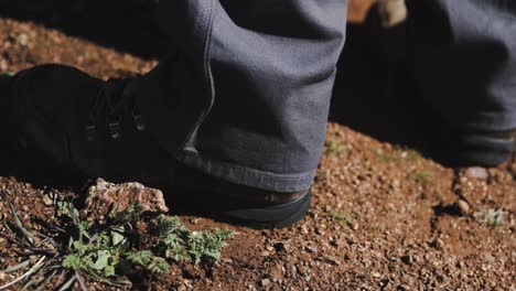 pan shot of a person wearing leather work boots with long pants standing dirt in the desert during a sunny day