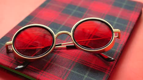 red round sunglasses on a plaid notebook