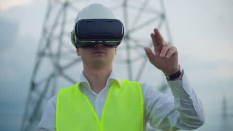 Mittelplan-Männlicher-Energieingenieur-Mit-Virtual-Reality-Brille-Und-Weißem-Helm-Auf-Dem-Hintergrund-Von-Hochspannungsmasten.