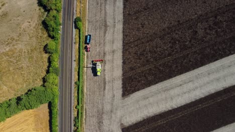 Aerial-footage-of-a-combine-harvester-preparing-to-deposit-feed-beans-into-a-tractor-trailer