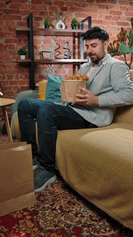 man taking a selfie while eating fried chicken at home