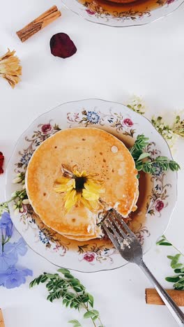delicious stacked pancakes with flowers and syrup